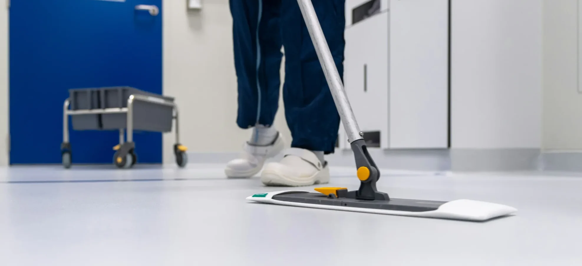 Uklízečka provádí úklid podlahy bytového domu v Praze pomocí mopu